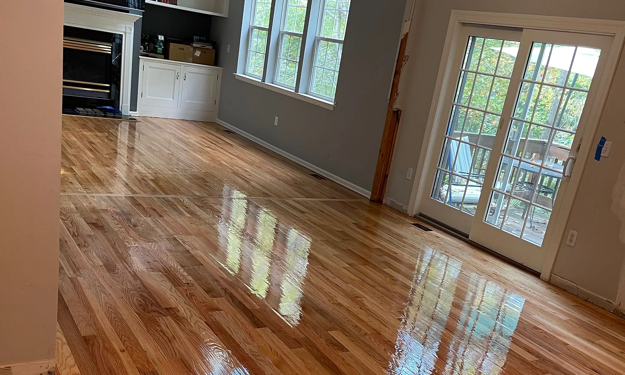 Living room hardwood floor after sanding and refinishing, glossy finish with sunlight
