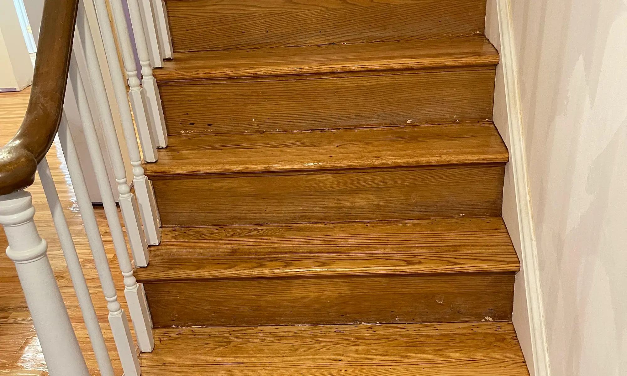 Refinished hardwood stair treads with a natural finish and white railing