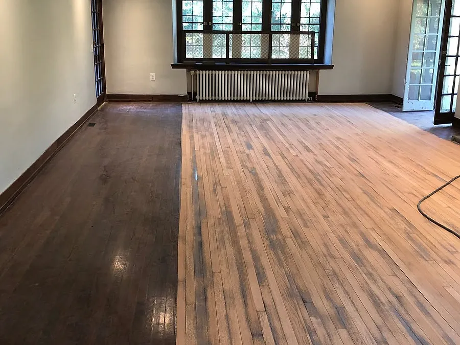 Large room with the old dark finish on one side and freshly sanded wood on the other