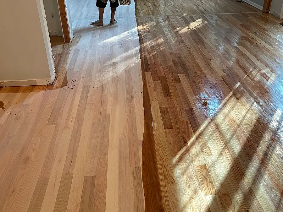 Finish being applied to a sanded hardwood floor, half done