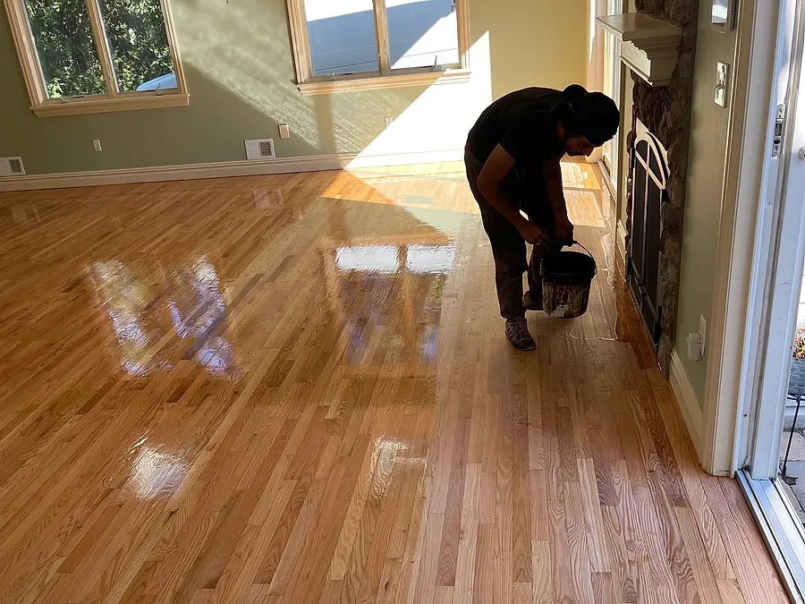 Freshly refinished hardwood living room with a VGJ crew member at work