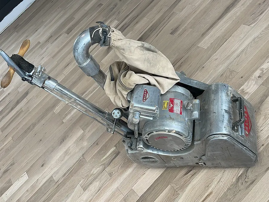 Drum floor sander on a hardwood floor sanded down to bare wood